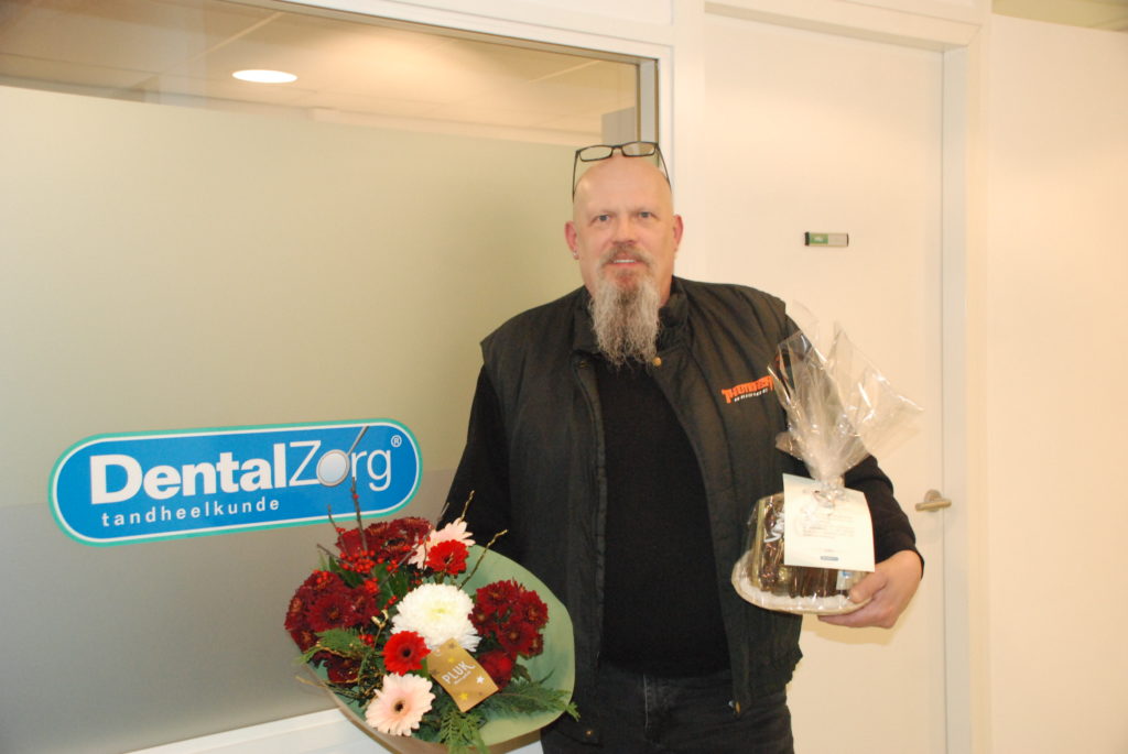 Tevreden patient met bloemen in de hand bij DentalZorg tandartspraktijk